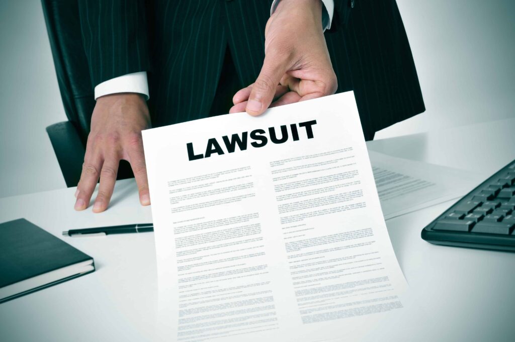 Lawyer in suit holding lawsuit document at desk representing legal action or civil litigation. Lawyer in suit holding lawsuit document at desk representing legal action or civil litigation.